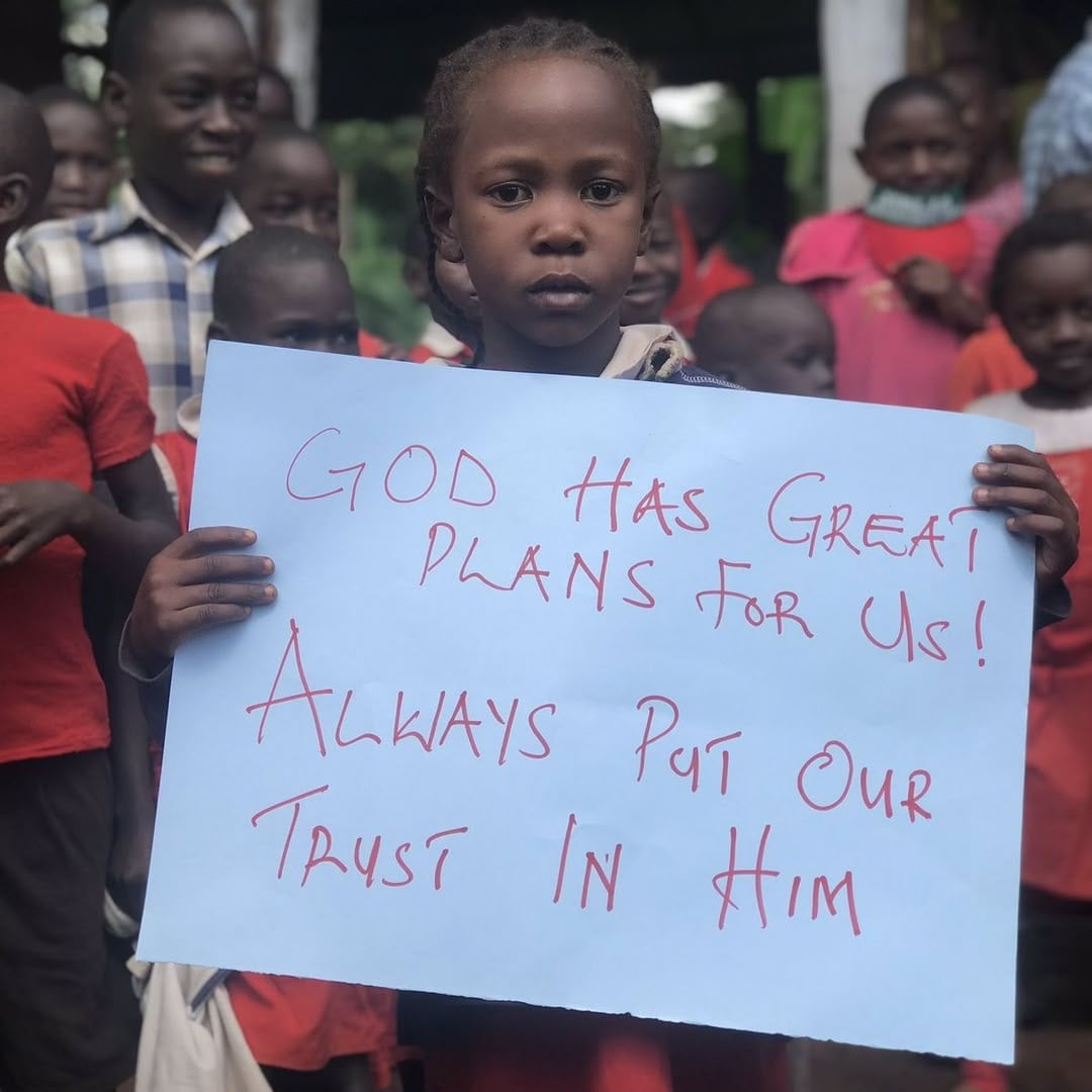 A girl holding a sign that reads: God has great plans for us