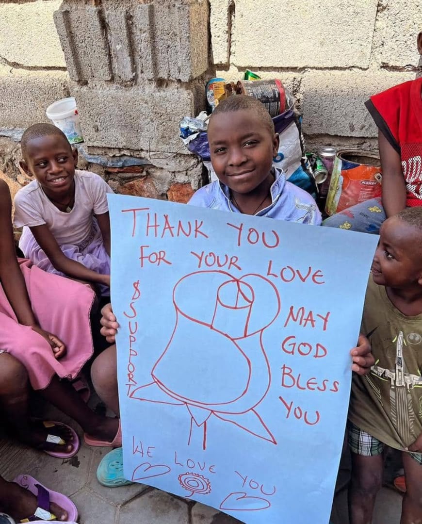 Children holding a hand-drawn thank-you sign