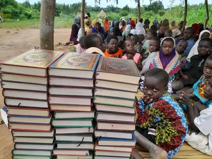 Stacks of donated books with children seated behind